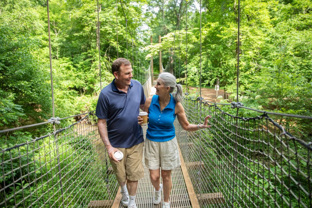 couple walking the bridge at Anne Springs Close Greenway in York County